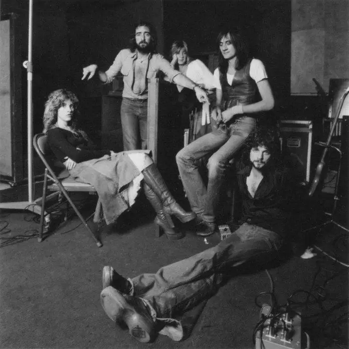 Black-and-white photograph of Fleetwood Mac gathered among chairs and recording equipment in a studio